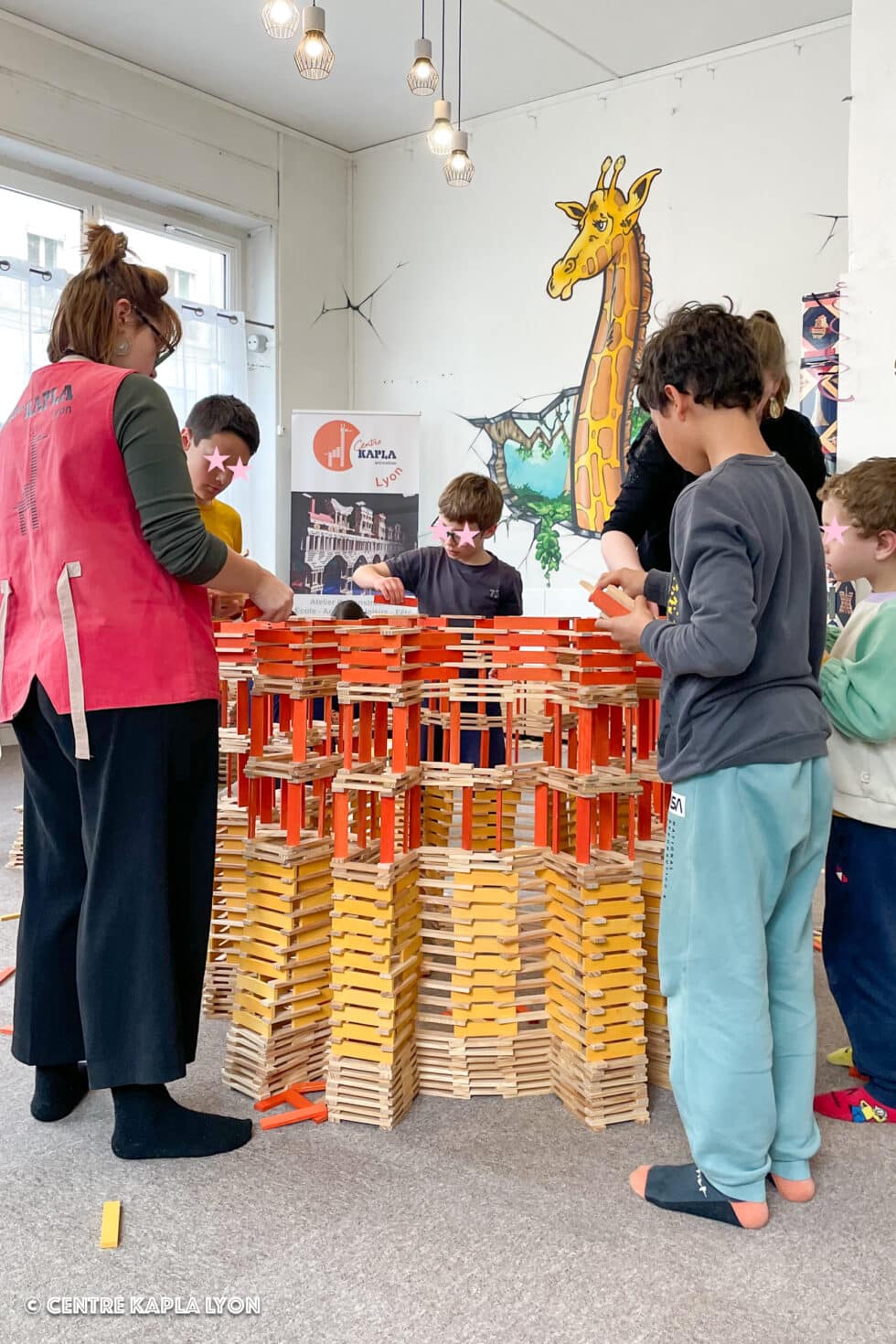 Des enfants réunis autour d'une construction en Kapla lors d'un atelier